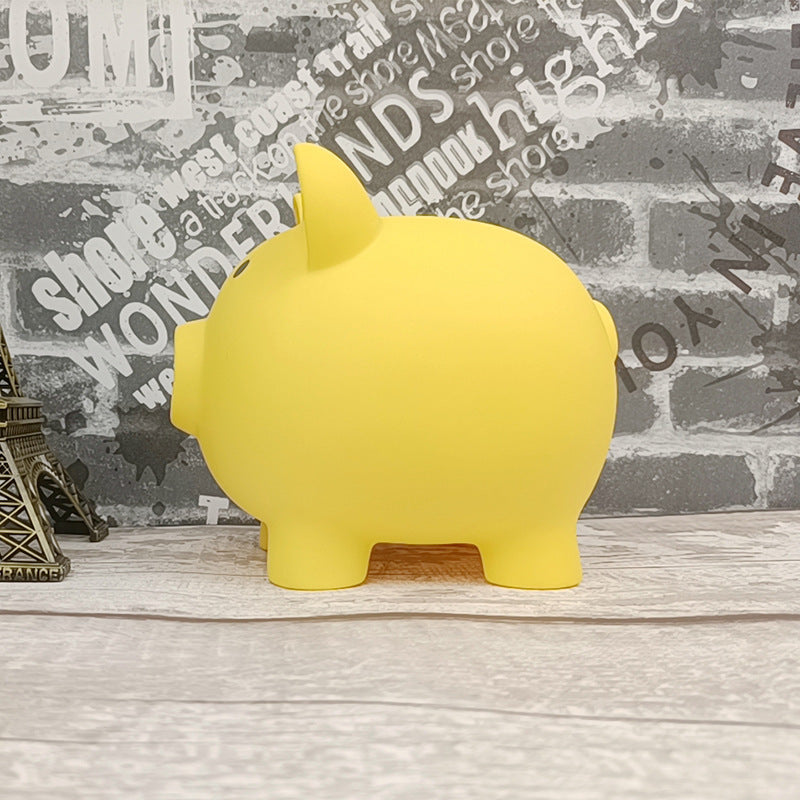Yellow piggy bank on a wooden surface with a decorative wall background