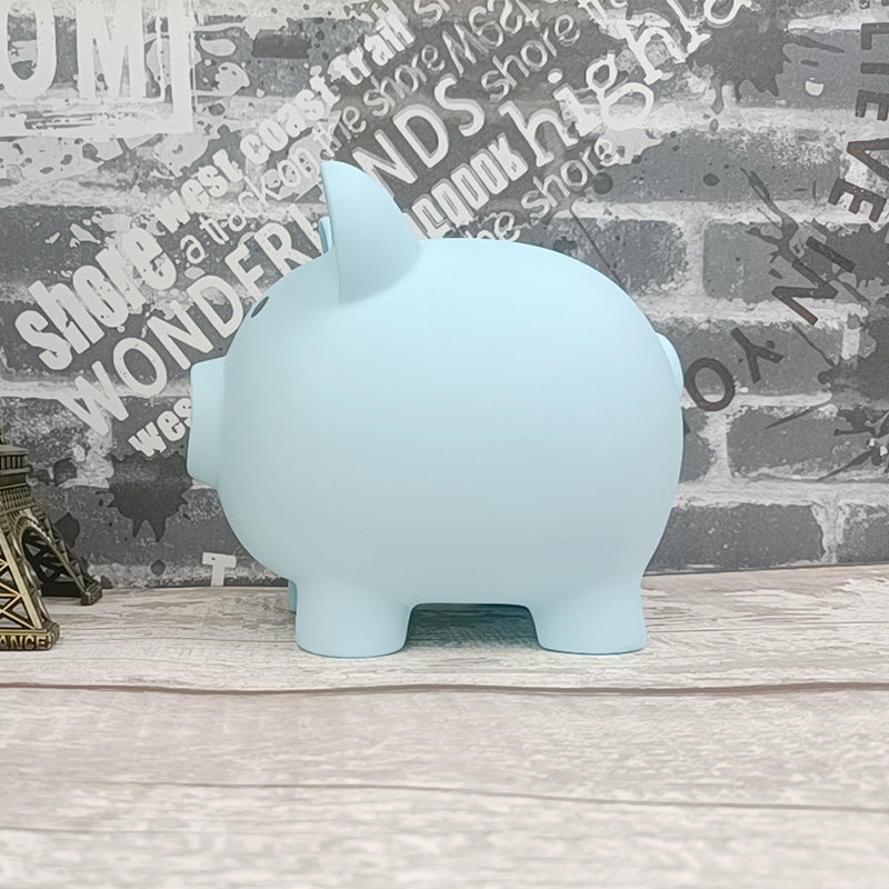 Light blue piggy bank on a wooden surface with a decorative wall background
