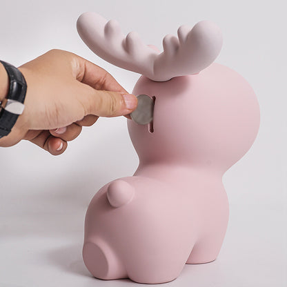 Pink moose-shaped piggy bank with a hand inserting a coin into its mouth against a light gray background. Piggy Bank.