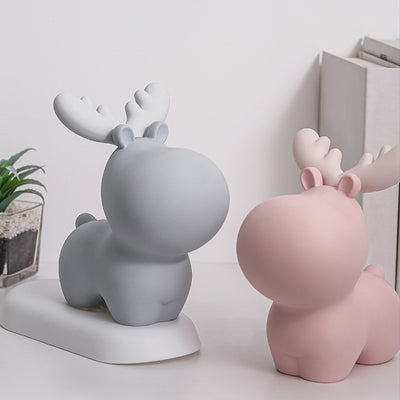 Two ceramic deer figurines, one gray and one pink, on a white surface with a light gray background. Piggy Bank.