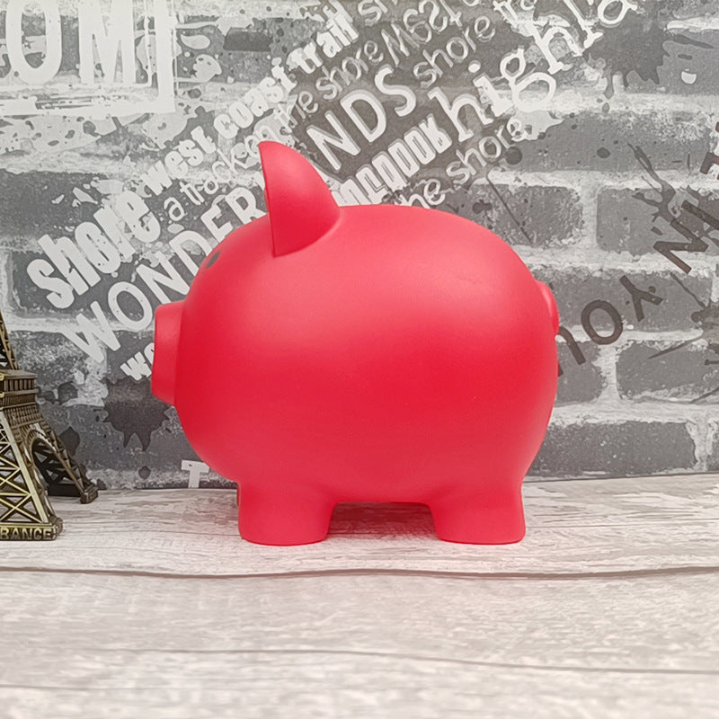 Red piggy bank on a wooden surface with a textured wall background