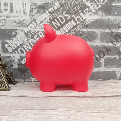 Red piggy bank on a wooden surface with a textured wall background