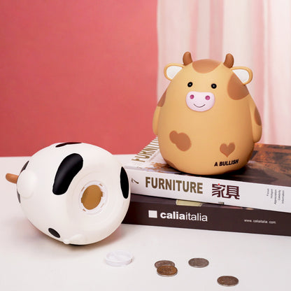 Two cow-shaped piggy banks on a magazine with a pink background