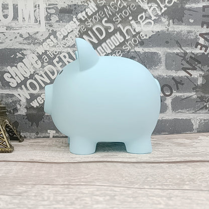 Light blue piggy bank on a wooden surface with a decorative wall background